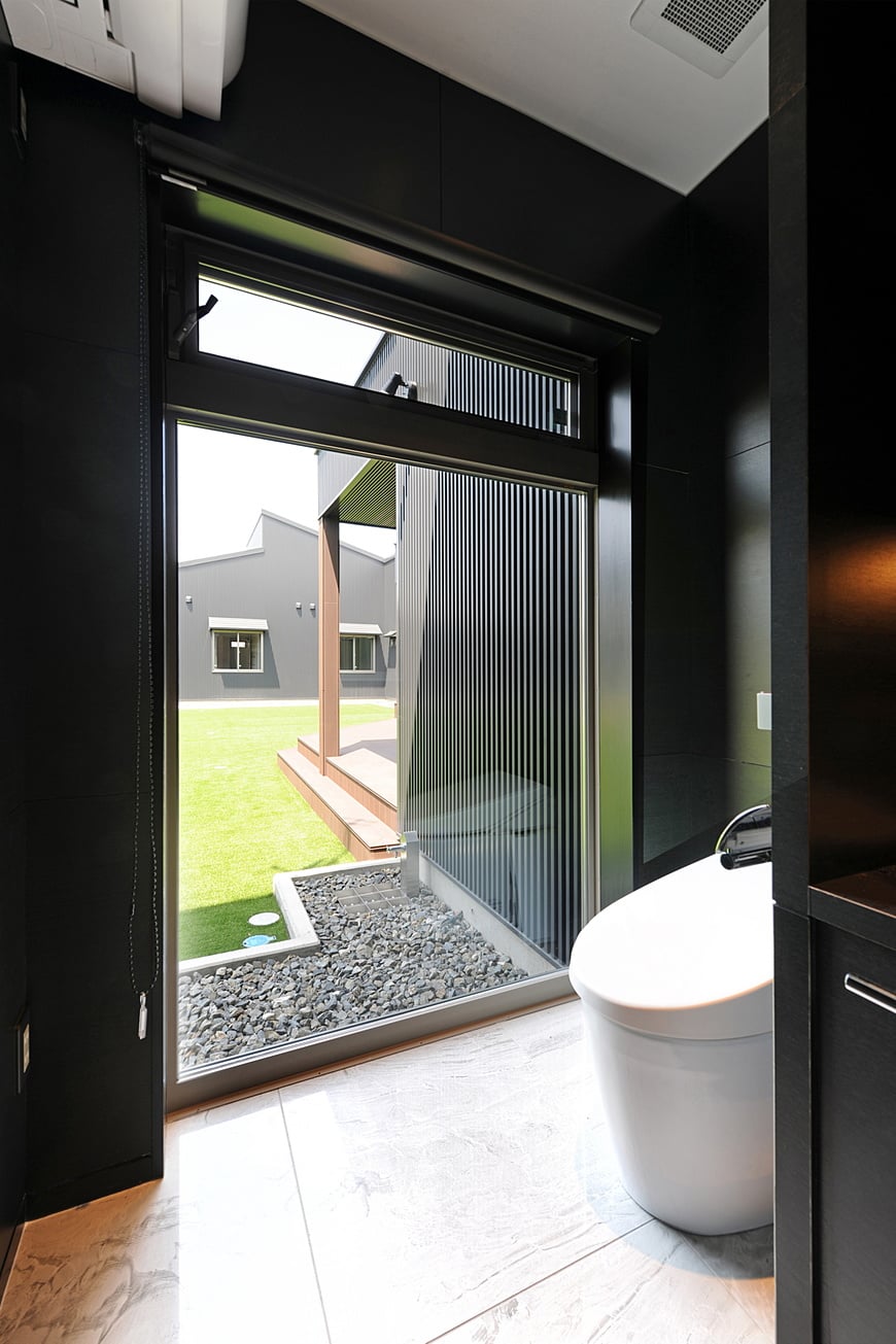 Restroom with the window greatly opened towards a courtyard