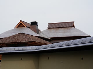 正門の桧皮葺屋根越しに暖炉棟屋根を見る